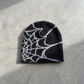 Black and ash web knit beanie laid flat, the jacquard spider web knitted into the fabric