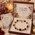 January Garnet birthstone bracelet with deep red faceted beads, pearl-style accents, gold-tone spacers and a Strength word charm